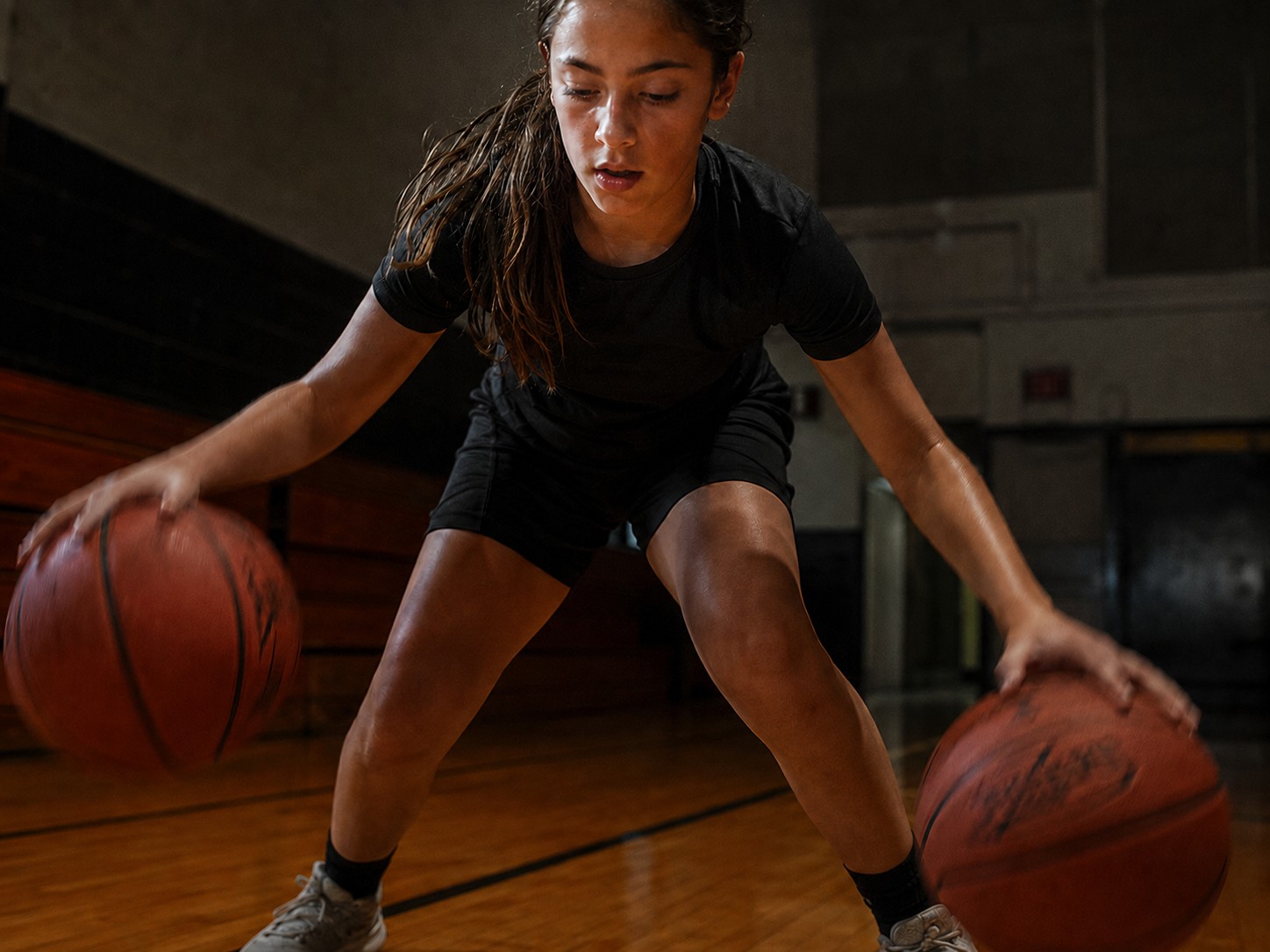 An athlete working on ball-handling with two basketballs during a private training session.